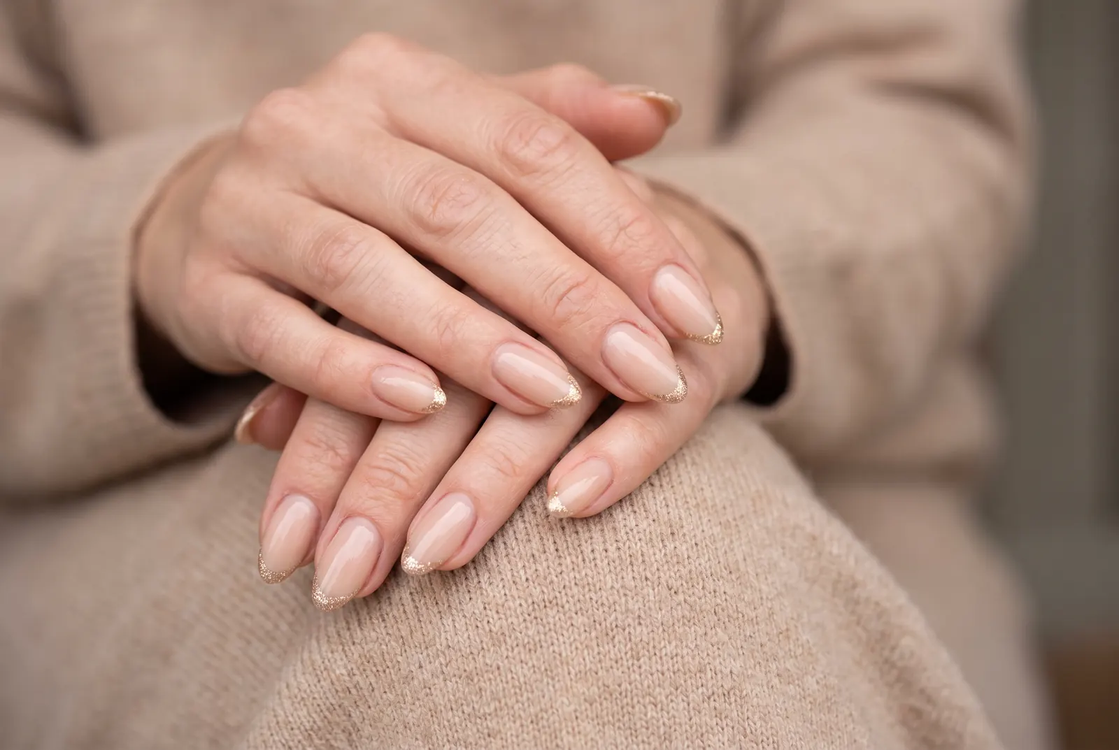 Nude amandelnagels met fijne gouden glitter in de tips
