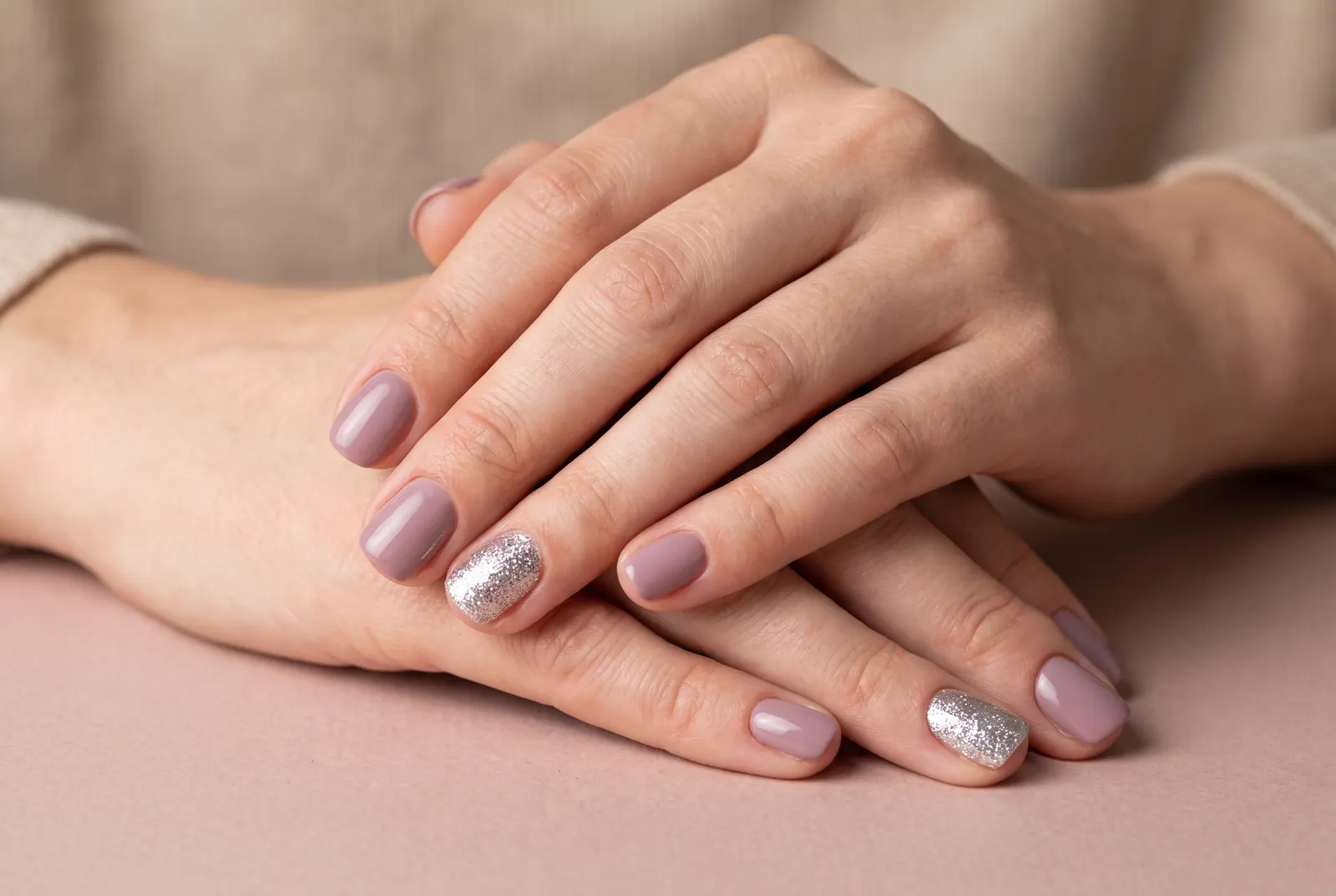 Mauve nagels met één volledig zilveren glitternagel op de ringvinger
